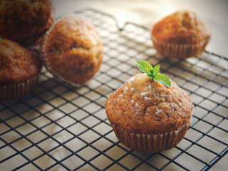 Banana cake or Muffins bakery placed on rack and brown cloth below, Decorate on top with Peppermint leaf and icing sugar, Activity or hobby making Cupcake at home in holiday.