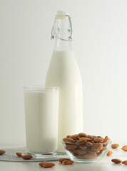 A glass with almond milk and the bowl with almonds