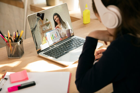 Little girl studying by group video call, use video conference with teacher, listening to online course. Using headphones, notebook. Easy, comfortable usage concept, education, online, childhood.