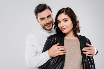 Smiling man wearing leather jacket on wife isolated on grey
