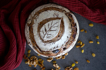 Sourdough bread on red textured background with raisins, olives and nuts. Autumn mood photo. Healthy eating concept.