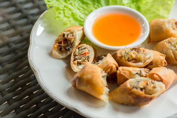 Vegan food concept. Deep-fries cut crispy spring roll with sweet and sour sauce served in a white plate.