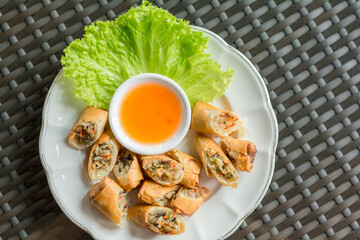 Vegan food concept. Deep-fries cut crispy spring roll with sweet and sour sauce served in a white plate.