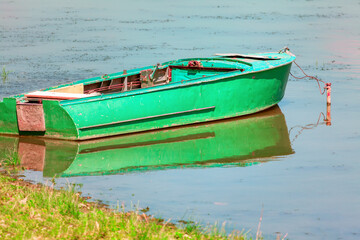Obraz premium Green fishing boat moored near to the shore . Old fishing vessel 