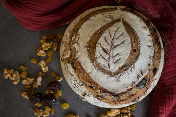 Close up photo of freshly baked rye sourdough bread, raisins, black olives and nuts on a table. Still life food. Artisan bread texture. 
