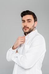 Brunette man in white shirt looking at camera isolated on grey