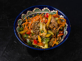 Korean salad with beef and pepper in a national bowl. Studio photo on black background