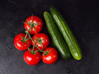 Red tomatoes and cucumber on a black background. Studio photo