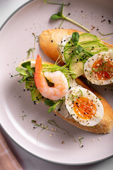 Breakfast with bruschetta with shrimps, eggs and microgreens in a plate