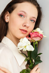 Obraz na płótnie Canvas young beautiful woman smelling a bunch of red roses. fashion interior photo of beautiful smiling woman with dark hair holding a big bouquet of red roses in Valentine's day