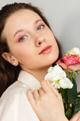 young beautiful woman smelling a bunch of red roses. fashion interior photo of beautiful smiling woman with dark hair holding a big bouquet of red roses in Valentine's day
