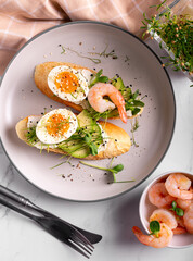Breakfast with bruschetta with shrimps, eggs and microgreens in a plate