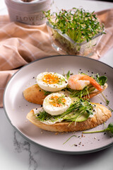 Breakfast with bruschetta with shrimps, eggs and microgreens in a plate