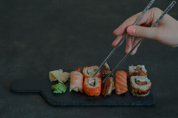 Asian sushi set with female hand holding chopsticks 
