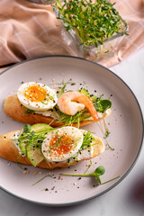 Breakfast with bruschetta with shrimps, eggs and microgreens in a plate