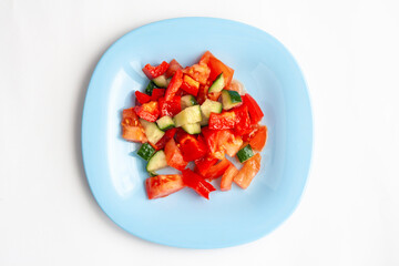 Vegetable salad in a blue plate, isolated on a white background, top view