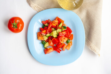 Healthy lunch, vegetable salad in a blue plate, tomato and olive oil in a bottle, top view