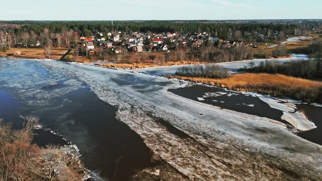 Small town at bank of river Gauja with melting ice and snow in Spring rising shot