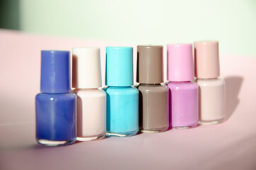 Group of pastel colored nail polishes isolated on pink bacground