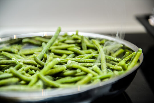 Close-up macro shot of metallic frying pan full with frozen french green long string beans