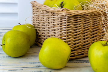 Green apples and basket with apples on wooden background