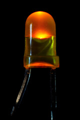 Glowing yellow LED with a diameter of 3 mm on a black background