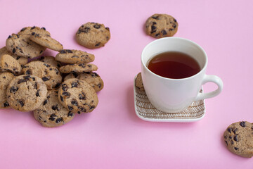 a cup of tea and a lot of cookies on a pink background. Overeating concept, sweet tooth. High quality photo