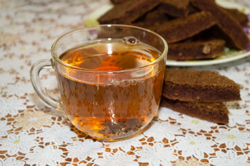 close-up - a transparent glass cup of tea with pieces of chocolate biscuit is on the table