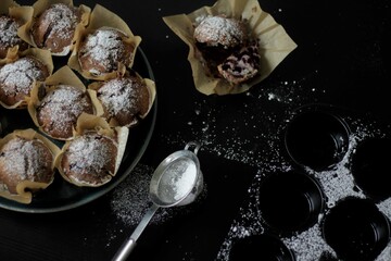 Fototapeta na wymiar Powdered muffins on a black table