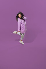 Talking phone. High angle view of young woman on purple studio background. Girl in motion. Human...