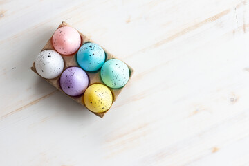 easter eggs in carton on white wood background