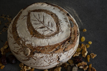 Sourdough bread with a leaf pattern on the top. Whole grain bread with black olives, raisins and nuts. Healthy eating concept.