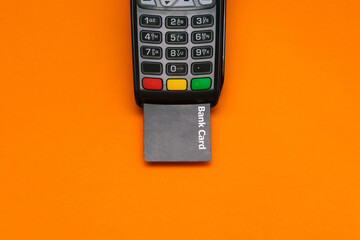 Electronic device for accepting payment cards. Modern POS payment terminal and bank card with copy space. Top view, flat lay