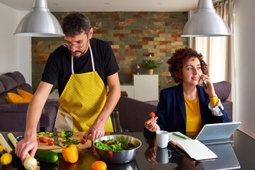 Young couple teleworking and making food