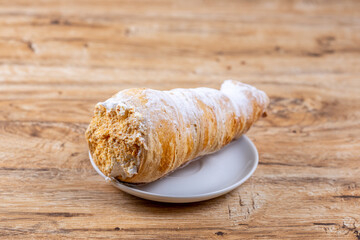 Delicious puff pastry cone with protein cream or whipped cream on wooden table