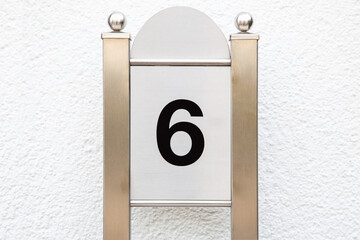 Close up of metallic house number "6"  on stainless steel pillar. Number six Door sign on metallic Column 