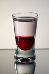 Single, reflected mad dog shot drink with tabasco sauce, raspberry syrup and chilli on side with smooth background