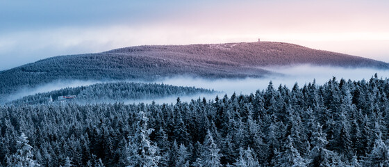 A view from the Orlica observation tower to the mountains with a snow-covered forest and an incoming fog. - obrazy, fototapety, plakaty