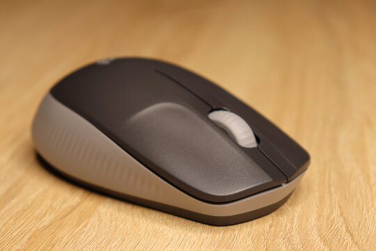 Computer mouse in gray color on a wooden background