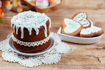 Easter still life with cake, homemade cookies and Easter eggs on a wooden table.