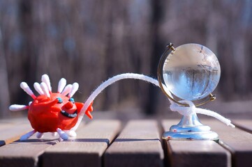 The figure of the virus is holding a rope tied to the globe. A concept symbol.