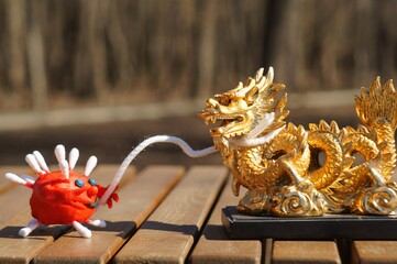 The virus figurine holds a rope binding the dragon figurine in its hand. A concept symbol.