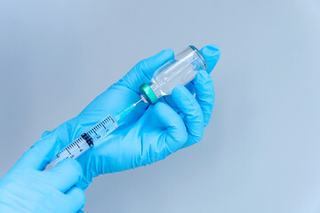 isolated on blue background: doctor's hand in glove holds a syringe vaccination against