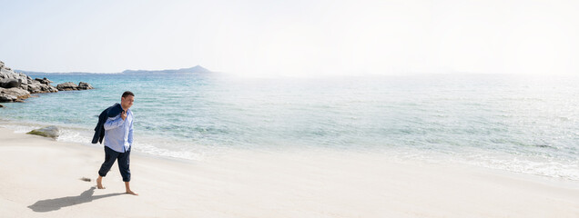 Horizontal banner with latin man with business suit walking on the shore in beautiful beach with nobody else.