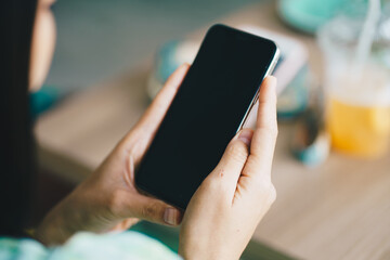 Woman hand holding smartphone black screen sittin in modern coffee shop