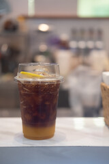 A plastic glass of espresso mixed with craft soda and orange juice and topping with orange slice.