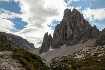 A panoramic view on Italian Dolomites. There are many high and sharp peak in front, with many landslides. Dangerous climbing. Barely any plants growing in the  area. Raw and unspoiled landscape.