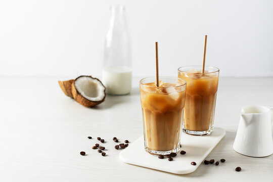 Iced Coffee With Coconut Milk In A Tall Glass On White Wooden Table.