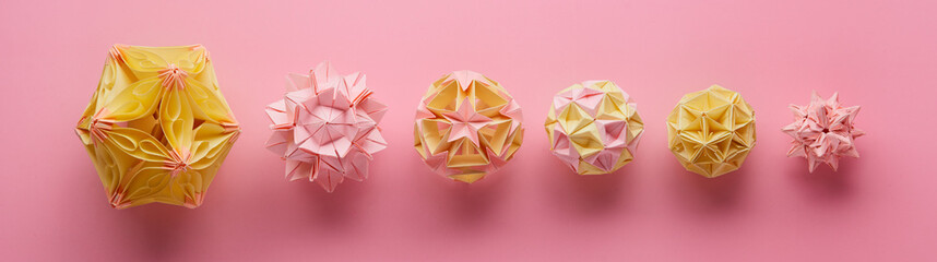 Set of multicolor handmade modular origami balls or Kusudama Isolated on pink background. Visual...