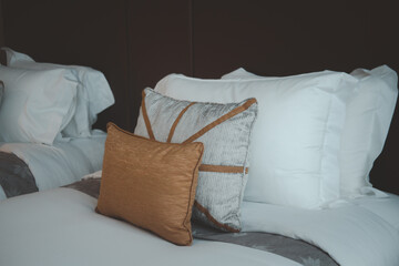 Brown and grey scatter cushion and a white sleeping pillow on a bed in bedroom